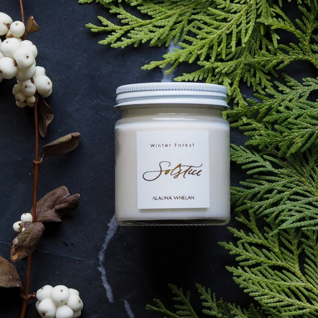 winter solstice luxury soy candle with cedar bough and white berries on black background